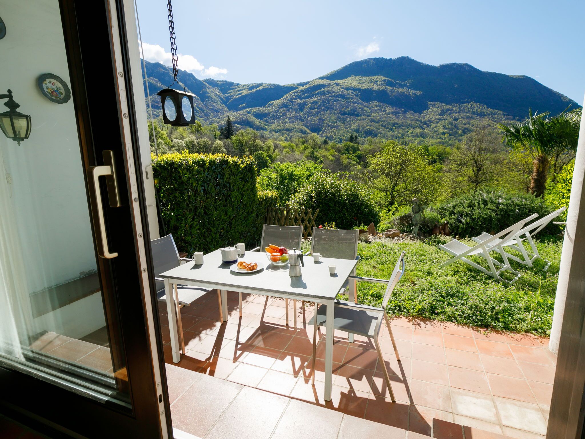 A patio with a table set for breakfast, overlooking a mountainous landscape.