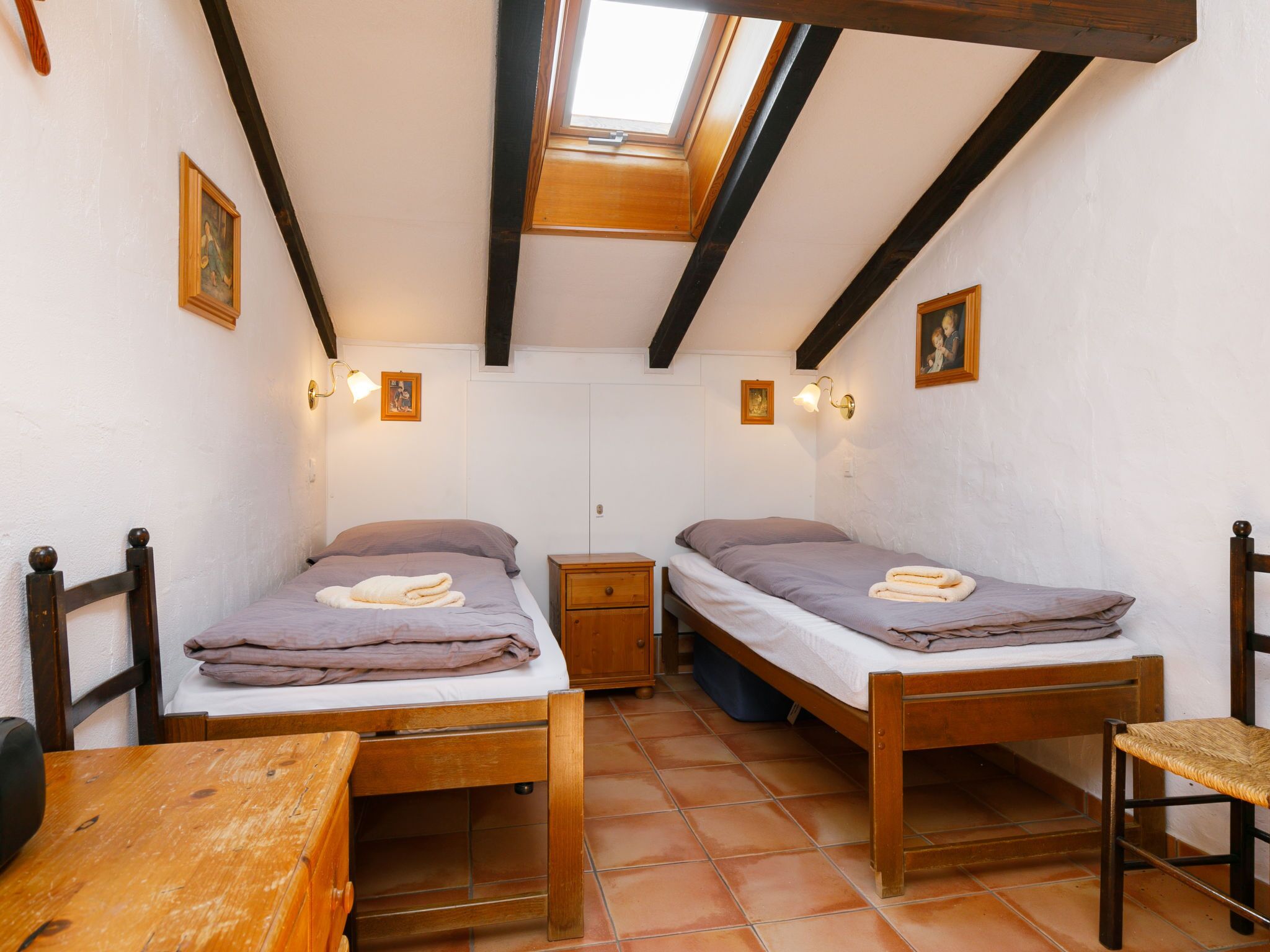 Una habitación pequeña y acogedora con dos camas de madera, una mesa de madera y un banco.