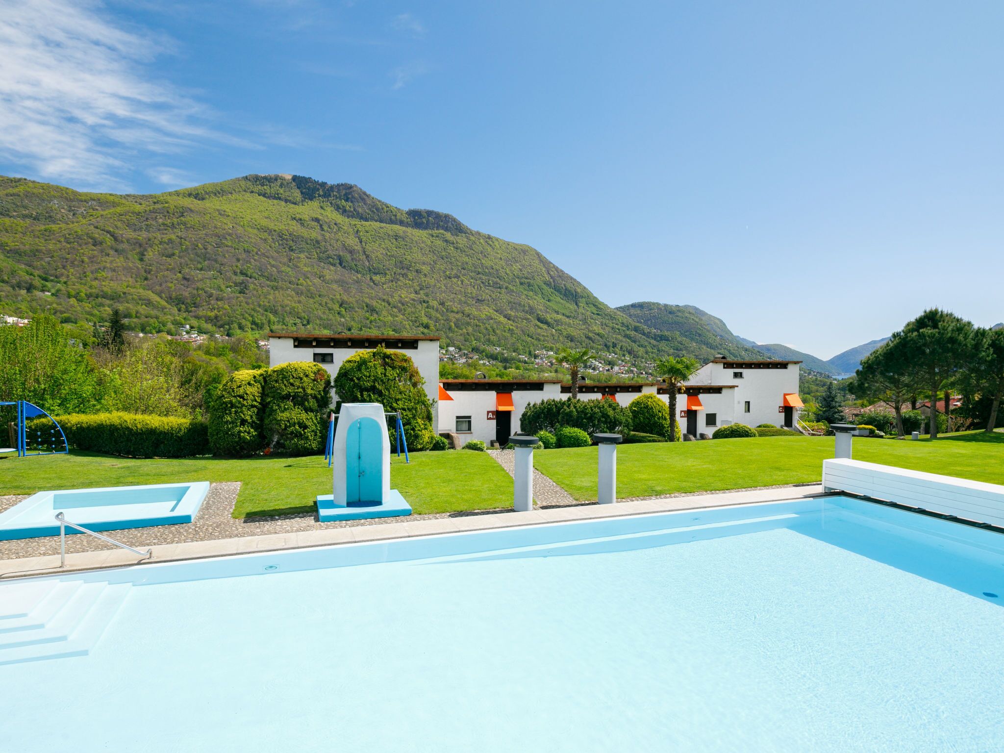 A swimming pool with a view of a mountain and a building with a red roof.