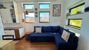 A modern living space with a sectional sofa, a dining table, and a kitchen area.