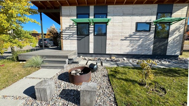 A modern building with a wooden deck, a fire pit, and a small garden area.