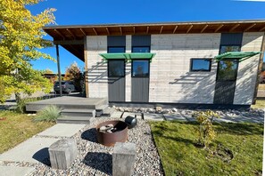 A modern building with a wooden deck, a fire pit, and a small garden area. - Chic Mountain Tiny Home Retreat in Victor w/AC (Victor)