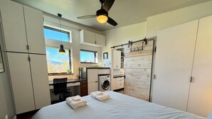 A bedroom with a bed, a desk, a washing machine, and a wardrobe.