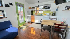 A compact kitchen with a dining area, a sofa, and a TV.
