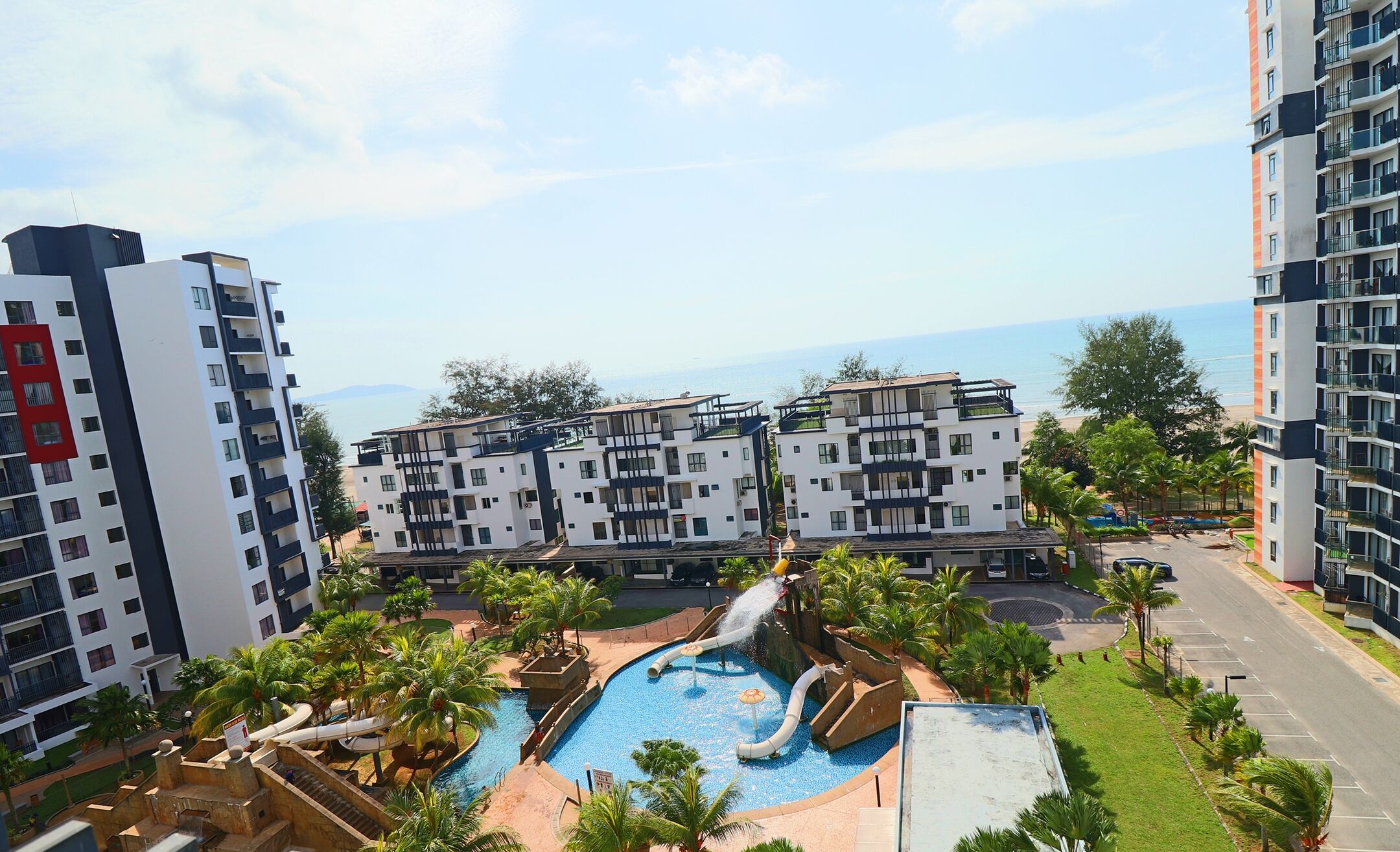 A modern apartment complex with a pool area featuring a water slide and multiple levels of balconies.