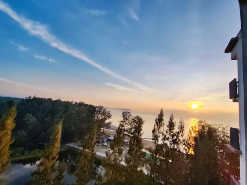 Een uitzicht op een zonsondergang boven een wateroppervlak met bomen op de voorgrond.