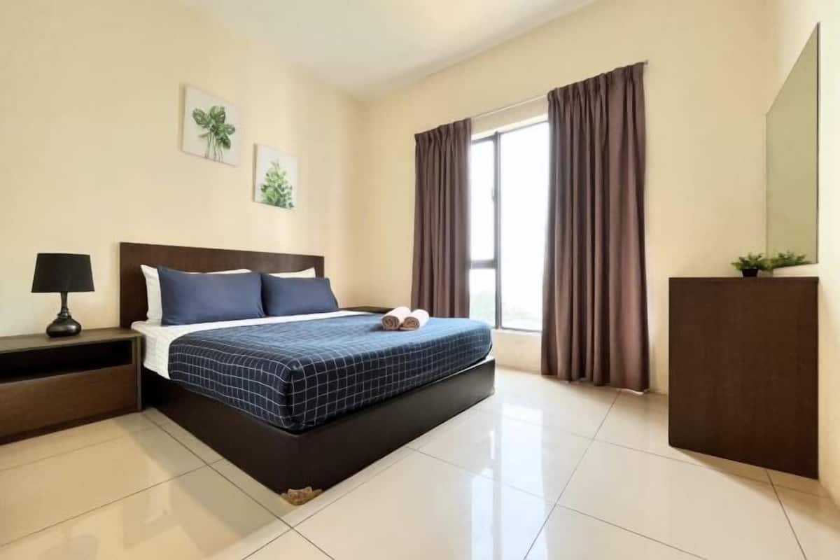 Une chambre d’hôtel avec un lit, une table de chevet, une lampe, une commode et une fenêtre avec des rideaux.
