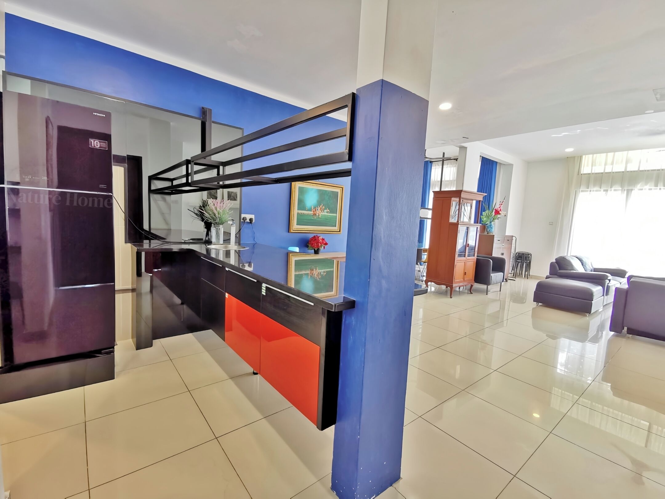 A modern kitchen with a black and red island, a refrigerator, and a blue accent wall.