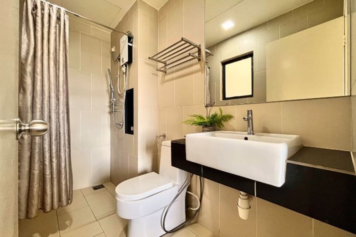 Un baño con inodoro, lavamanos, ducha y perchero para toallas.