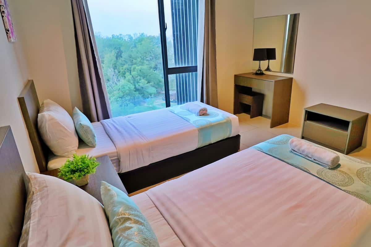 Une chambre d’hôtel avec deux lits, un petit bureau, un miroir et une fenêtre donnant sur des arbres.