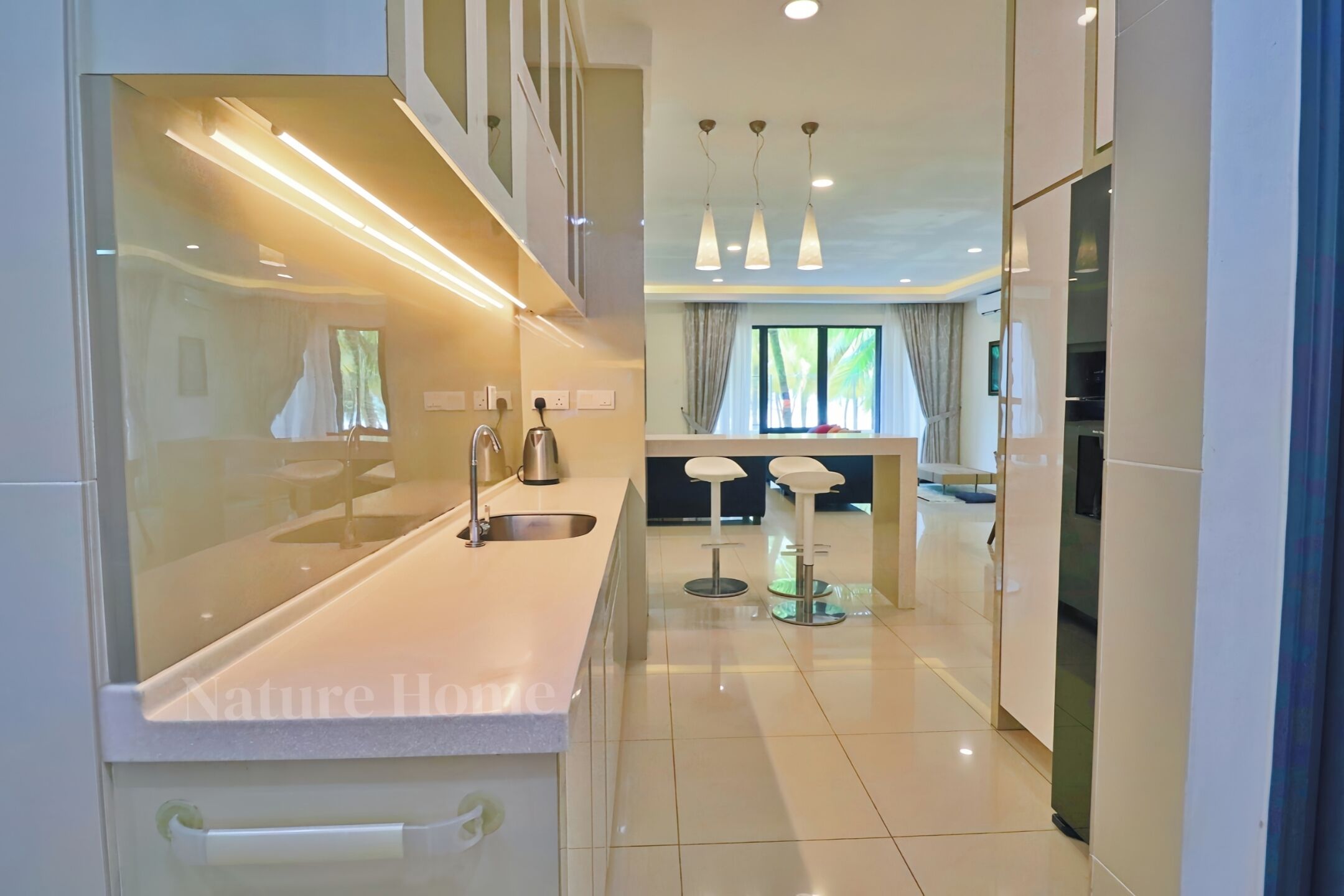 A modern kitchen with a central island, pendant lighting, and a view to the dining area.