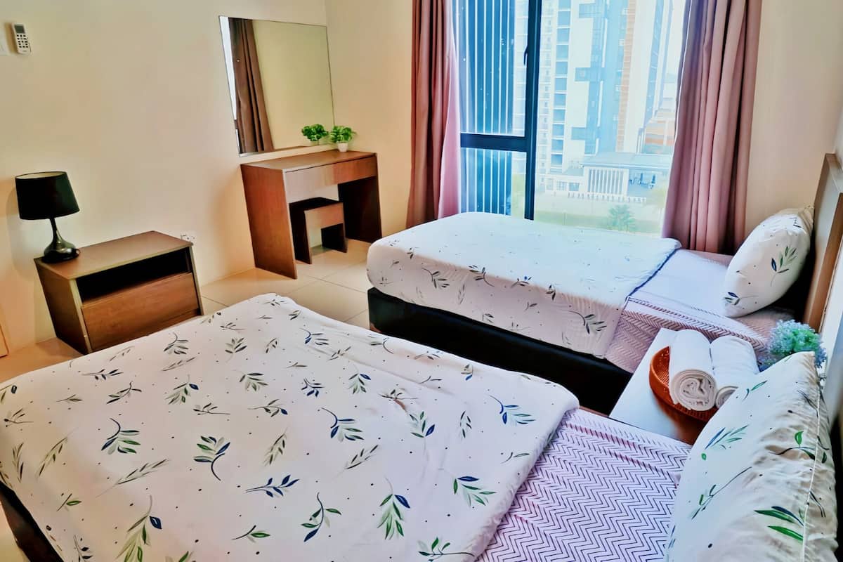 Une chambre d’hôtel avec deux lits, un bureau, une lampe et une vue sur les grands immeubles par la fenêtre.