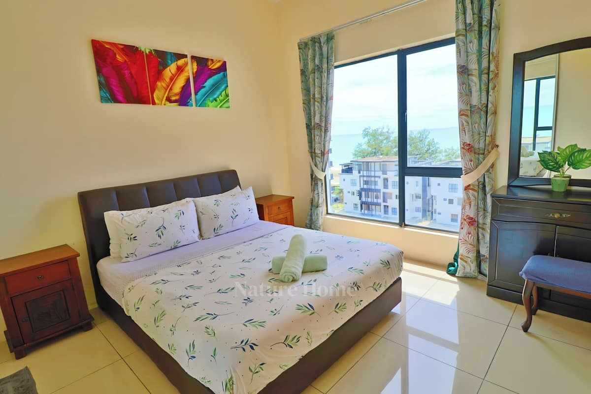 Une chambre à coucher avec un lit, une table de chevet, une commode, une fenêtre avec des rideaux et un tableau au mur.