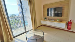 A modern living room with a glass table, a mounted TV, a white console, and a fire extinguisher. - Swiss Garden Residences by Nature Home (Balok)