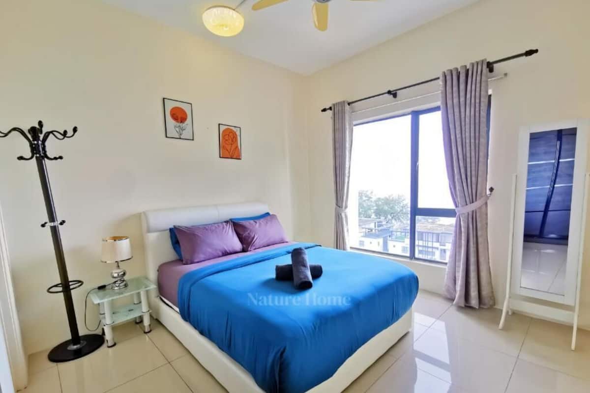 Une chambre à coucher comprenant un lit, une table de chevet, une lampe sur pied, une fenêtre avec des rideaux et une vue sur l’extérieur.