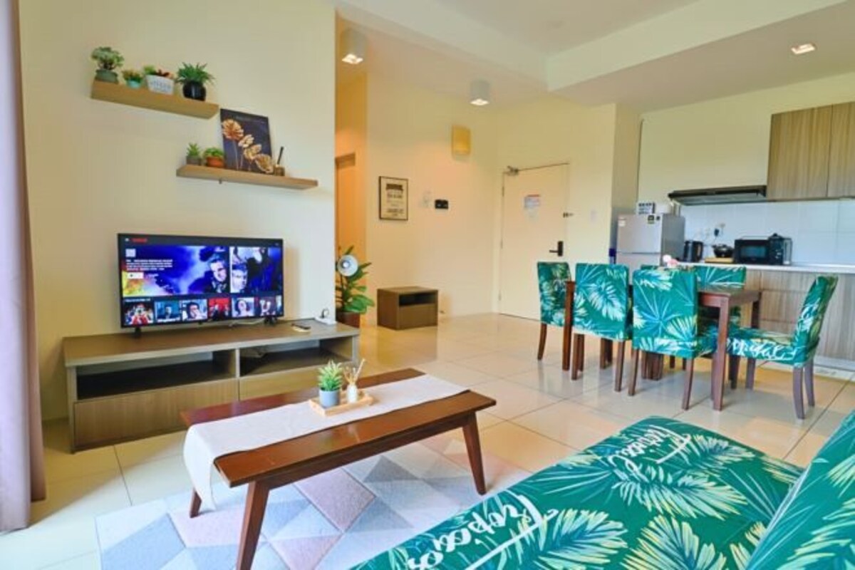 Una sala de estar con televisor, sofá, mesa de centro y un comedor con sillas.