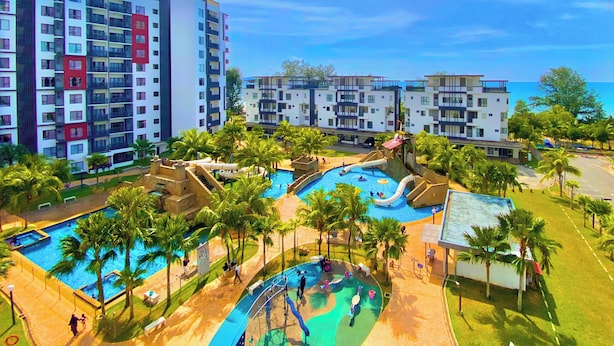 A resort with multiple swimming pools, palm trees, and a view of the ocean. - Swiss Garden Residences by Nature Home (Balok)