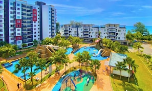 A resort with multiple swimming pools, palm trees, and a view of the ocean.