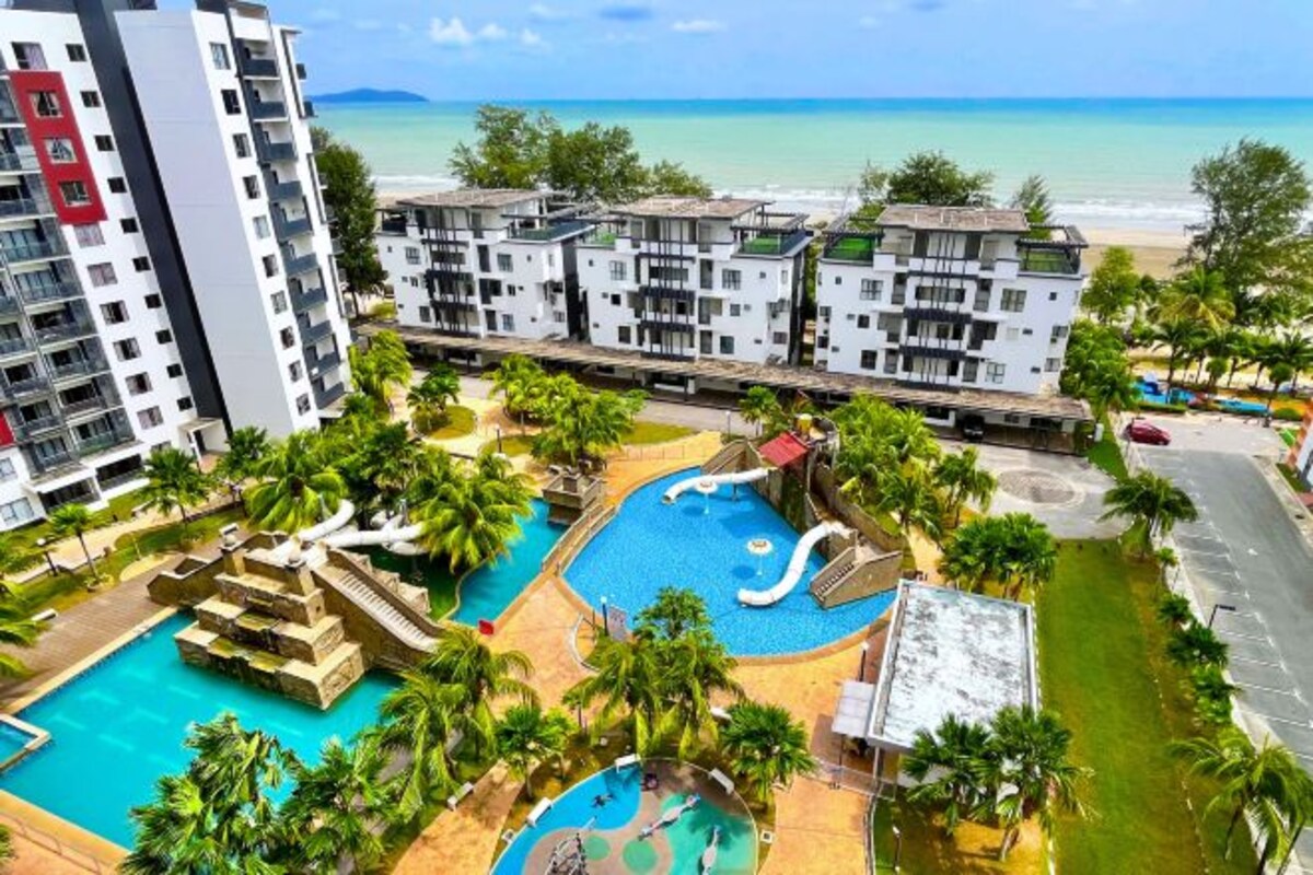Un resort con piscina, palmeras y vista a la playa.