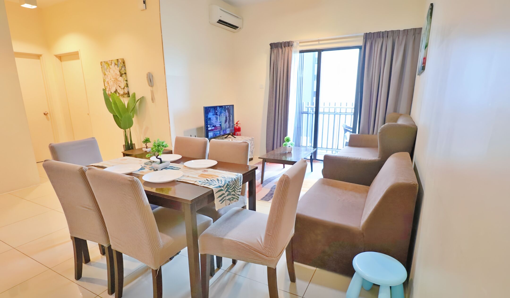 A dining area with a table set for four, surrounded by chairs, and a sofa with a small stool.