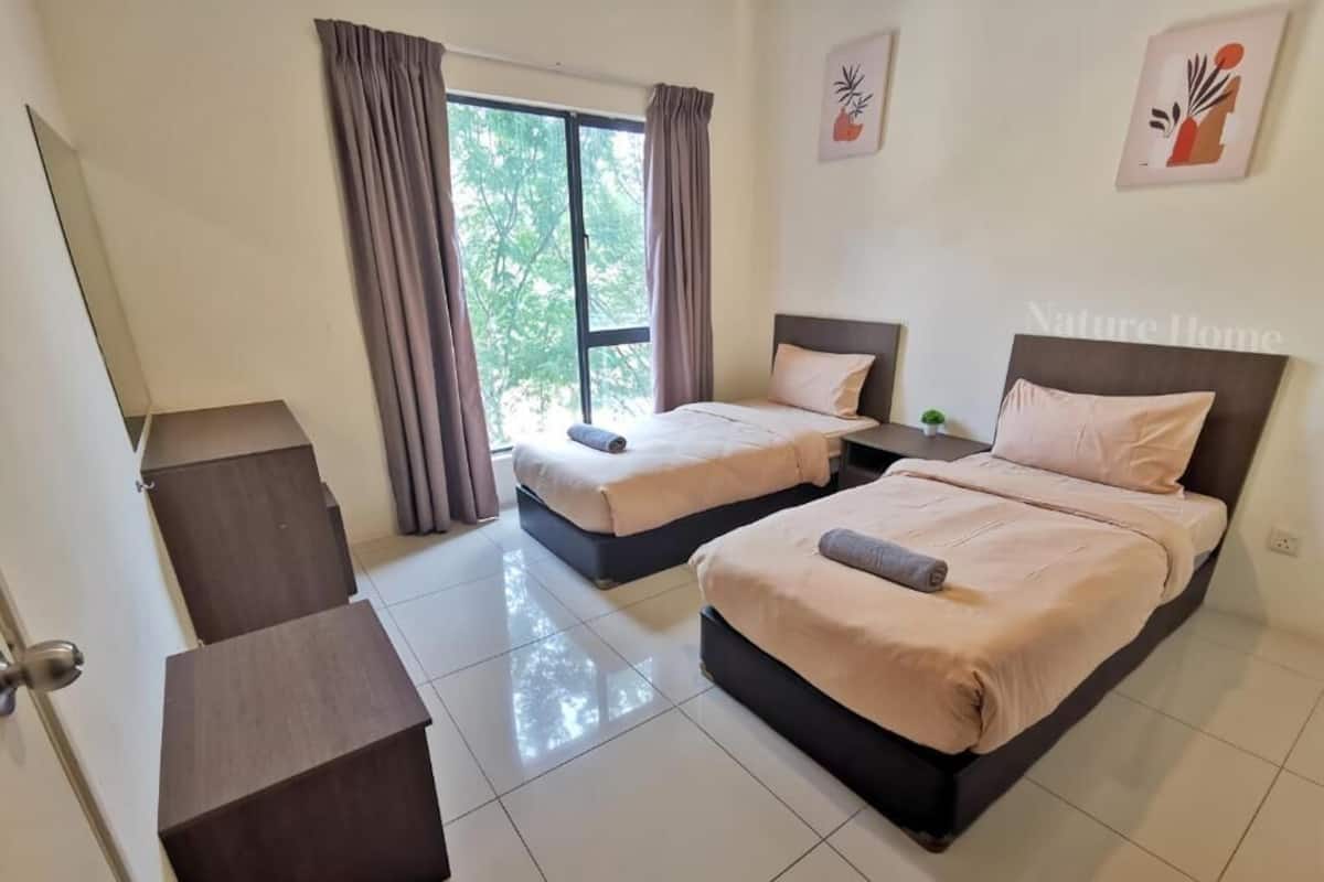 Une chambre d’hôtel avec deux lits, une fenêtre avec des rideaux, une petite table et un placard.