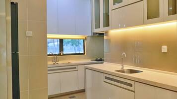 Una cocina moderna con armarios blancos, un lavamanos de acero inoxidable y un ventanal que proporciona luz natural.