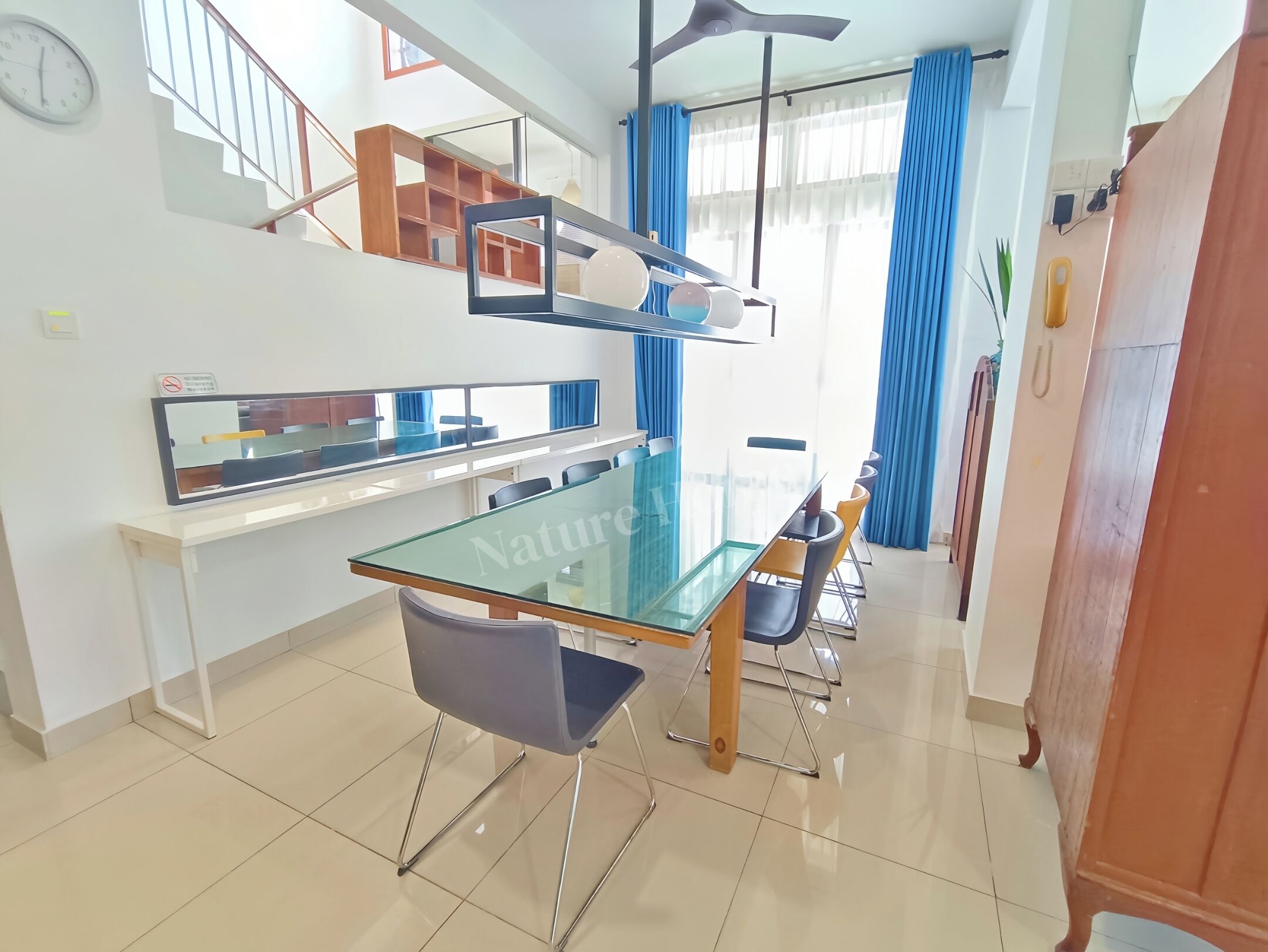 A modern dining area with a glass table and chairs, a staircase, and a view of the outside.