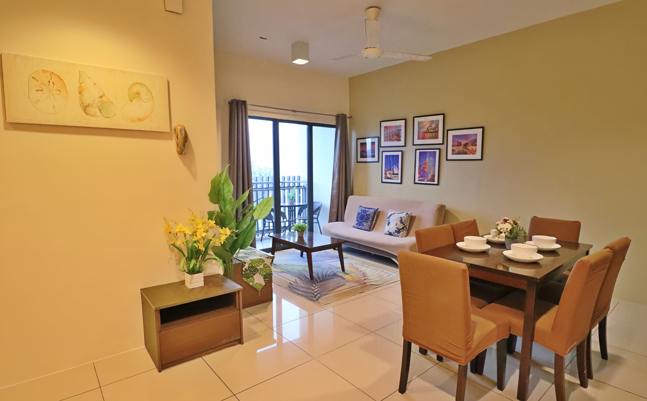 A dining area with a table set for four, a sofa, and a balcony with a view.