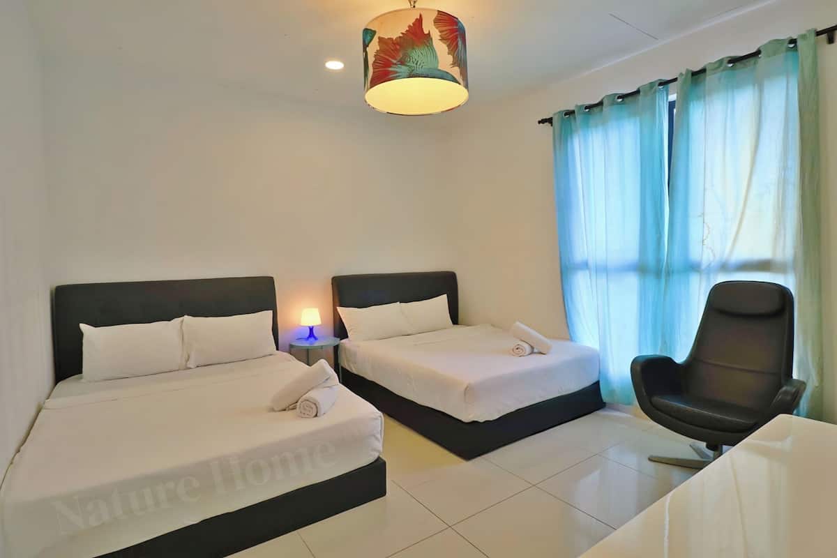 Une chambre d’hôtel avec deux lits, un bureau, une chaise et une lampe.