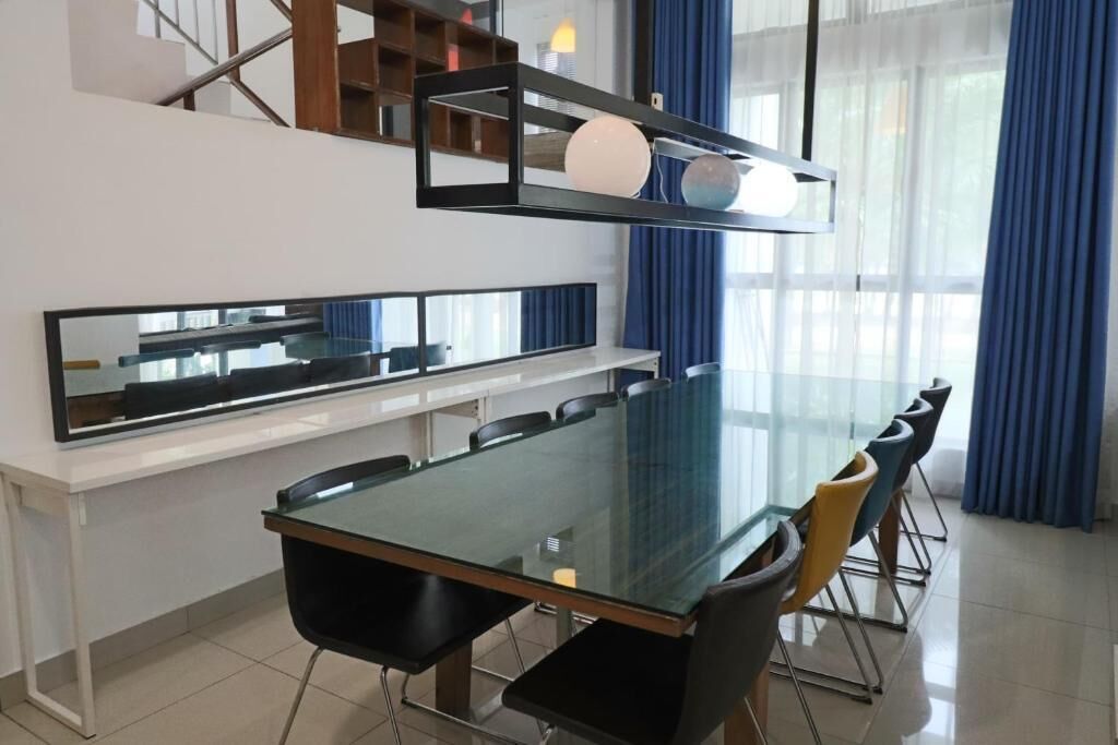 A modern dining area with a glass table, black chairs, and a white console table.