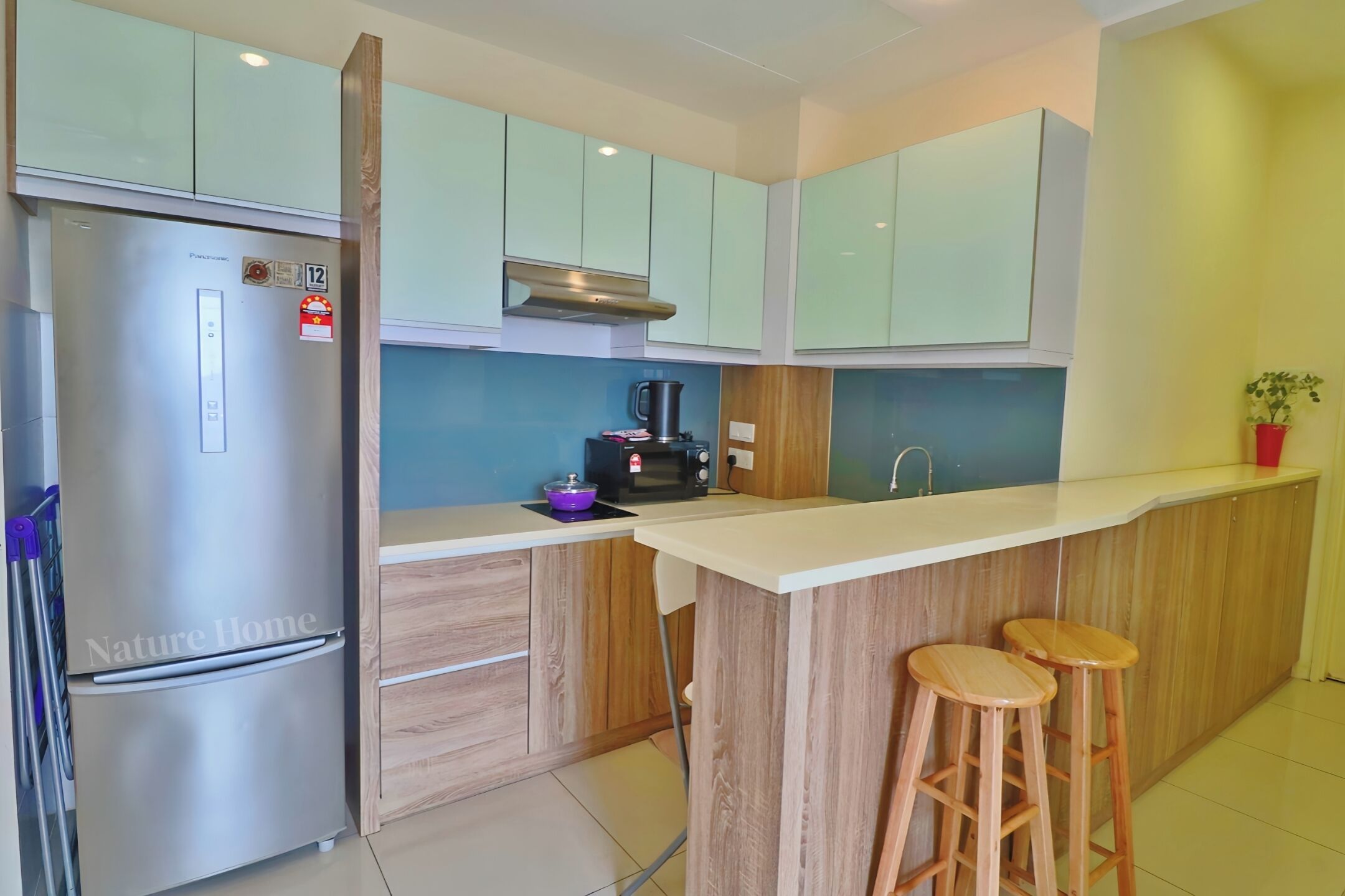 A modern kitchen with a stainless steel refrigerator, wooden cabinets, a microwave, and a coffee maker.