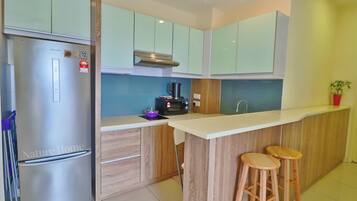 A modern kitchen with a stainless steel refrigerator, wooden cabinets, a microwave, and a coffee maker.