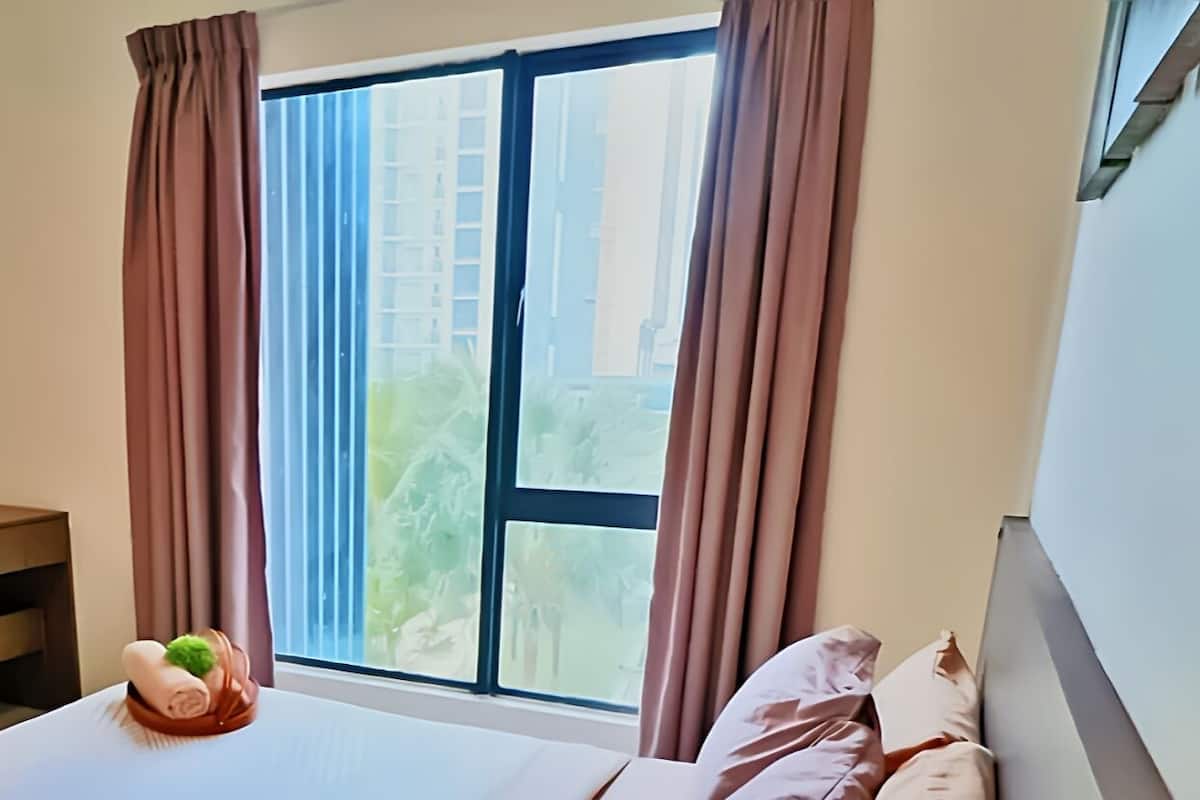 Une chambre d’hôtel avec un lit, une petite table agrémentée d’un objet décoratif, un miroir et une fenêtre avec des rideaux.