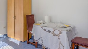 Et spiseområde med et bord dækket til fire personer, en træskab og en stol.