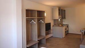 A compact kitchen with a built-in oven, microwave, and sink. There is a small seating area with a table and chairs. - Apartamentos Pontepedriña by Bossh (Santiago de Compostela)