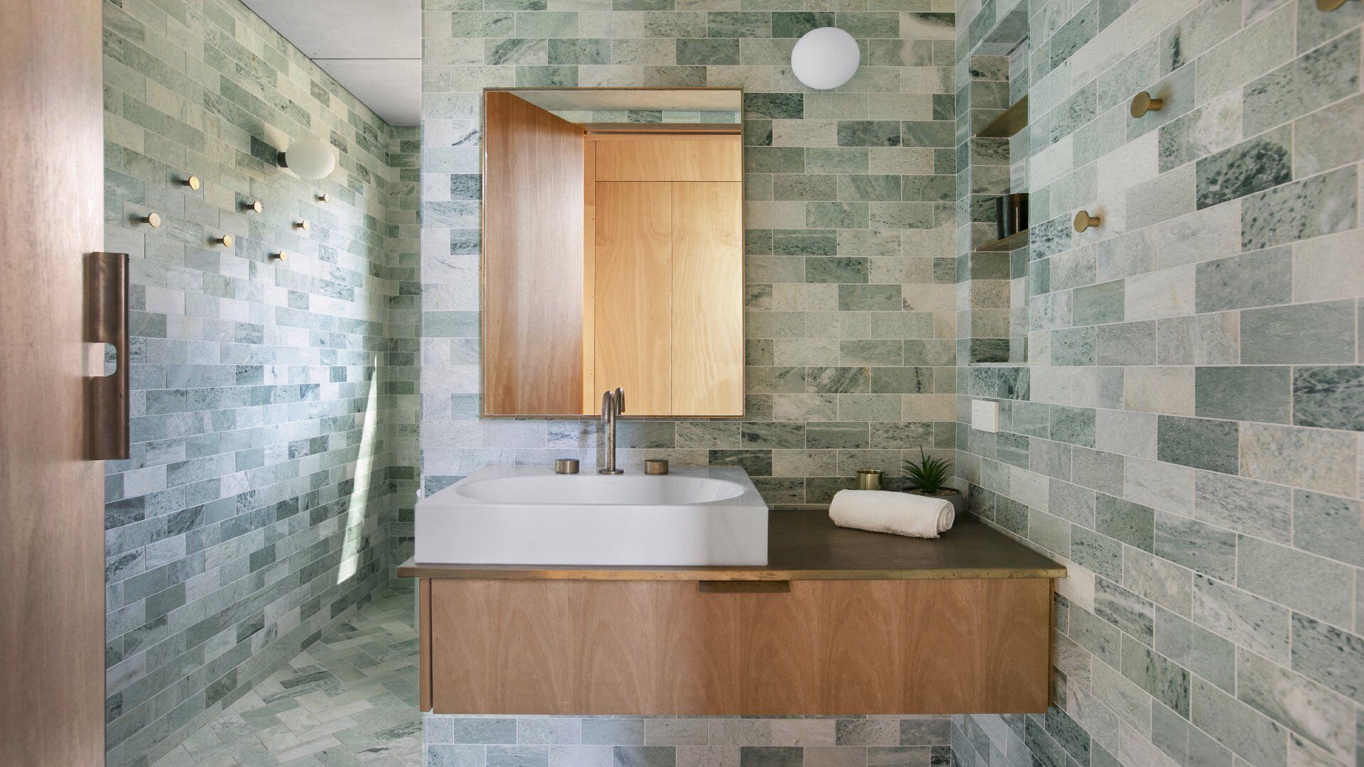 A modern bathroom with a wooden vanity, a large mirror, and a sink.