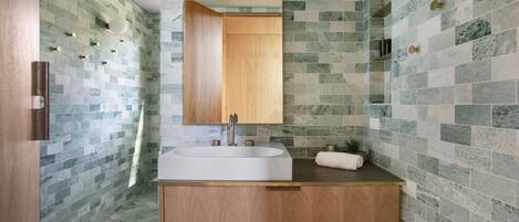 A modern bathroom with a wooden vanity, a large mirror, and a sink.