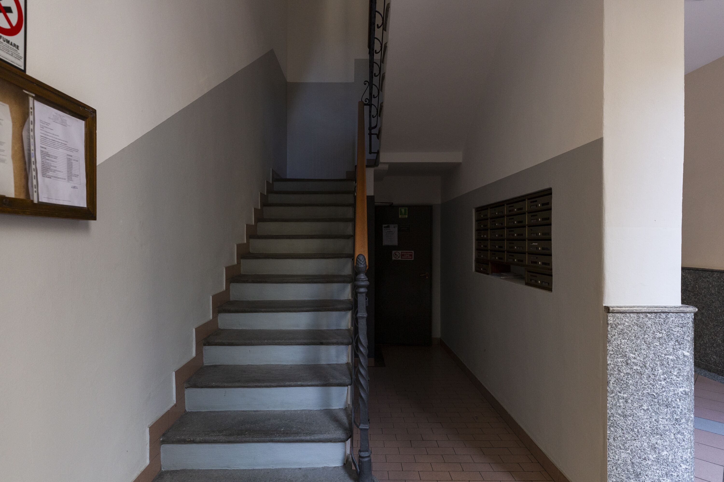 A staircase with a handrail, a wall-mounted sign, and a door at the bottom.