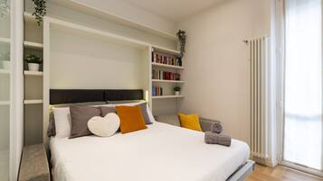 Une chambre à coucher avec un lit, des tables de chevet, une bibliothèque et un radiateur.