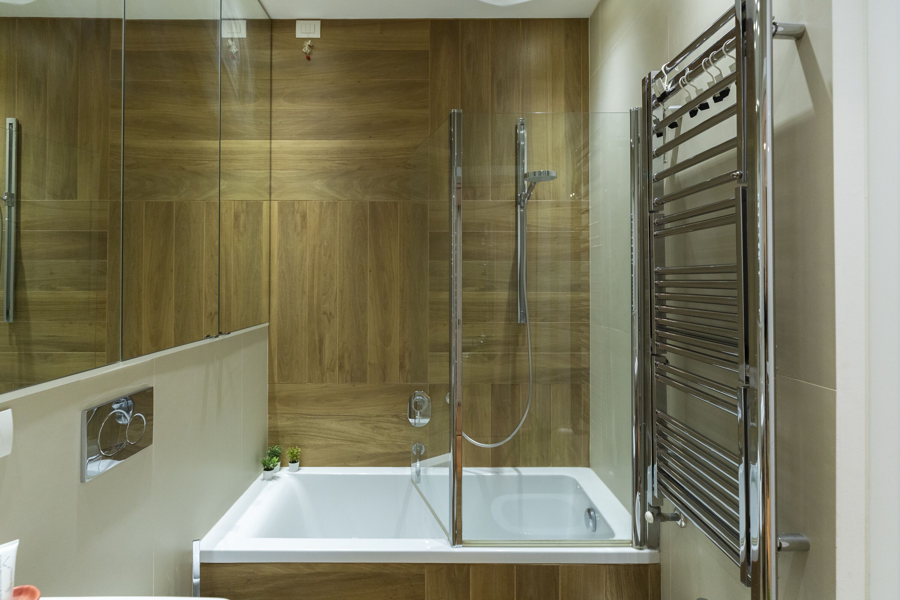 Une salle de bain moderne avec une douche à parois de verre, une baignoire blanche et un lambris en bois sur les murs.