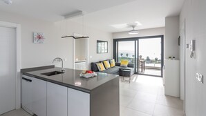 Eine moderne Küche mit einer zentralen Kochinsel, ein Essbereich mit einer Couch und einem Tisch sowie ein Balkon mit Blick.