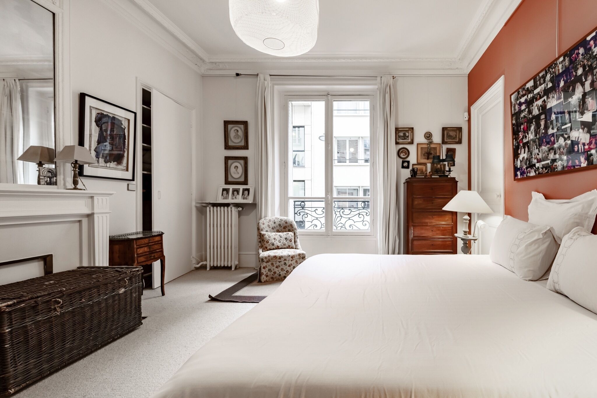 Habitación de hotel con una cama grande, un aparador de madera, una silla, un radiador y una ventana con vistas al balcón.
