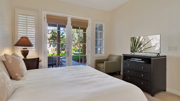 A bedroom with a bed, a dresser, a chair, and a television.