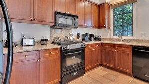 Une cuisine avec des meubles de rangement en bois, un four à micro-ondes, une cuisinière et un lave-vaisselle.