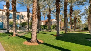 A courtyard with palm trees, a hammock, and a building with a tiled roof. - Desert Haven B | Studio Legacy Villa (La Quinta)
