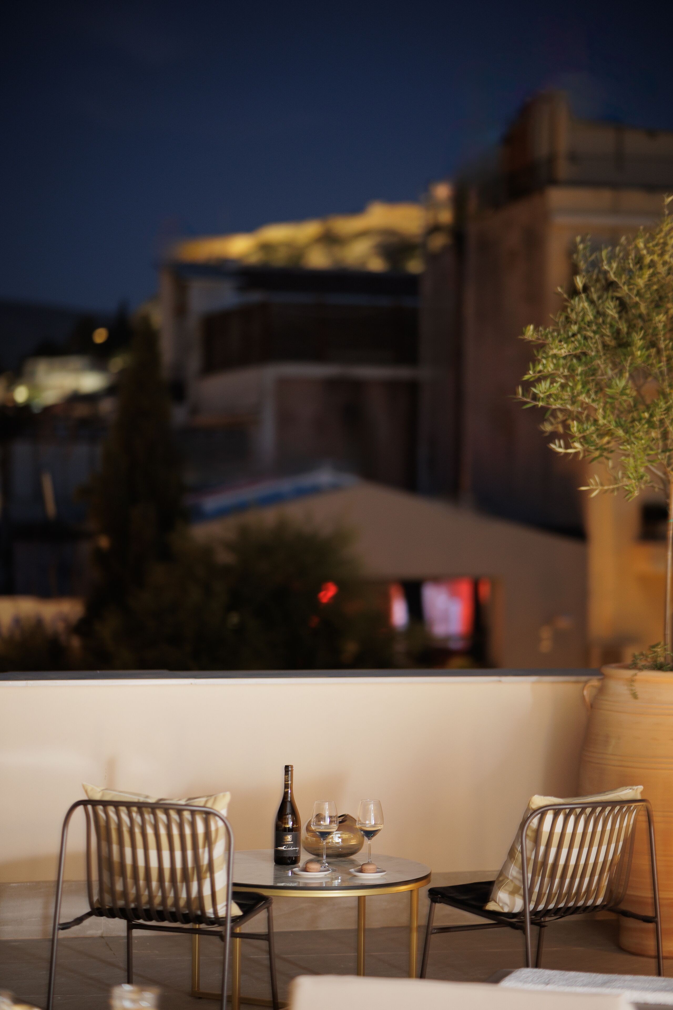 Un espace extérieur aménagé avec deux chaises, une table et une bouteille de vin.