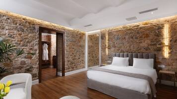 Quarto com parede de pedra, cama com roupa de cama branca e piso de madeira.