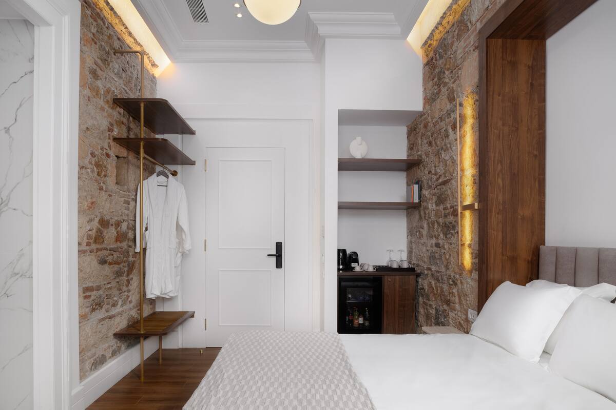 A modern bedroom with a brick wall, a wooden bed frame, and built-in shelves.