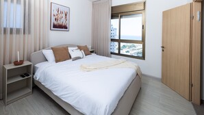 Una camera da letto ordinata con un letto, comodini, una finestra con vista e una porta.