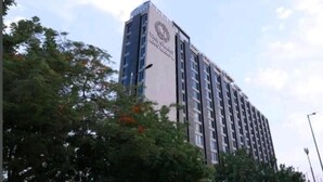 Un edificio de varios pisos con un logotipo destacado en la fachada, rodeado de árboles.